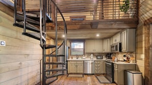 A kitchen with wooden walls, a spiral staircase, stainless steel appliances, and a window. - A Little Stoney River - Cartecay River in Ellijay (Ellijay)