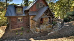 Eine rustikale Holzhütte mit Steinunterbau und einem steilen Satteldach.