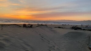A beach with sand dunes, a few beach chairs, and a lifeguard tower in the distance. - Multi Family Home 2 min walk to beach, Sleeps 13 (Oceano)