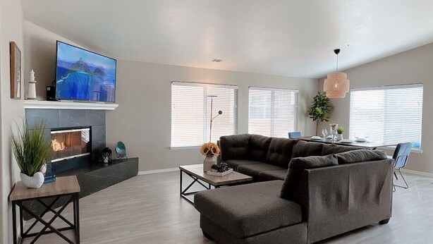 A modern living room with a fireplace, a large flat-screen TV, and a sectional sofa. - Multi Family Home 2 min walk to beach, Sleeps 13 (Oceano)