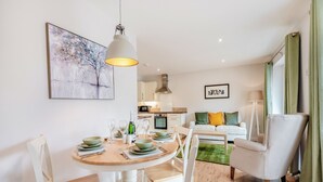 Ein modernes Wohnzimmer mit Essbereich, einer Küche im Hintergrund und einem grünen Teppich.