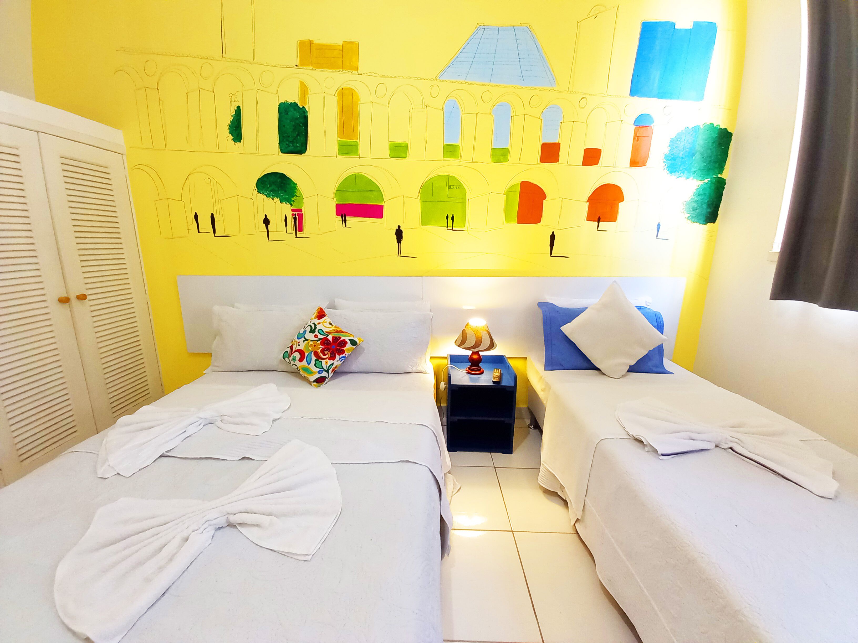 Une chambre d’hôtel avec deux lits, une table de chevet et une fresque murale.