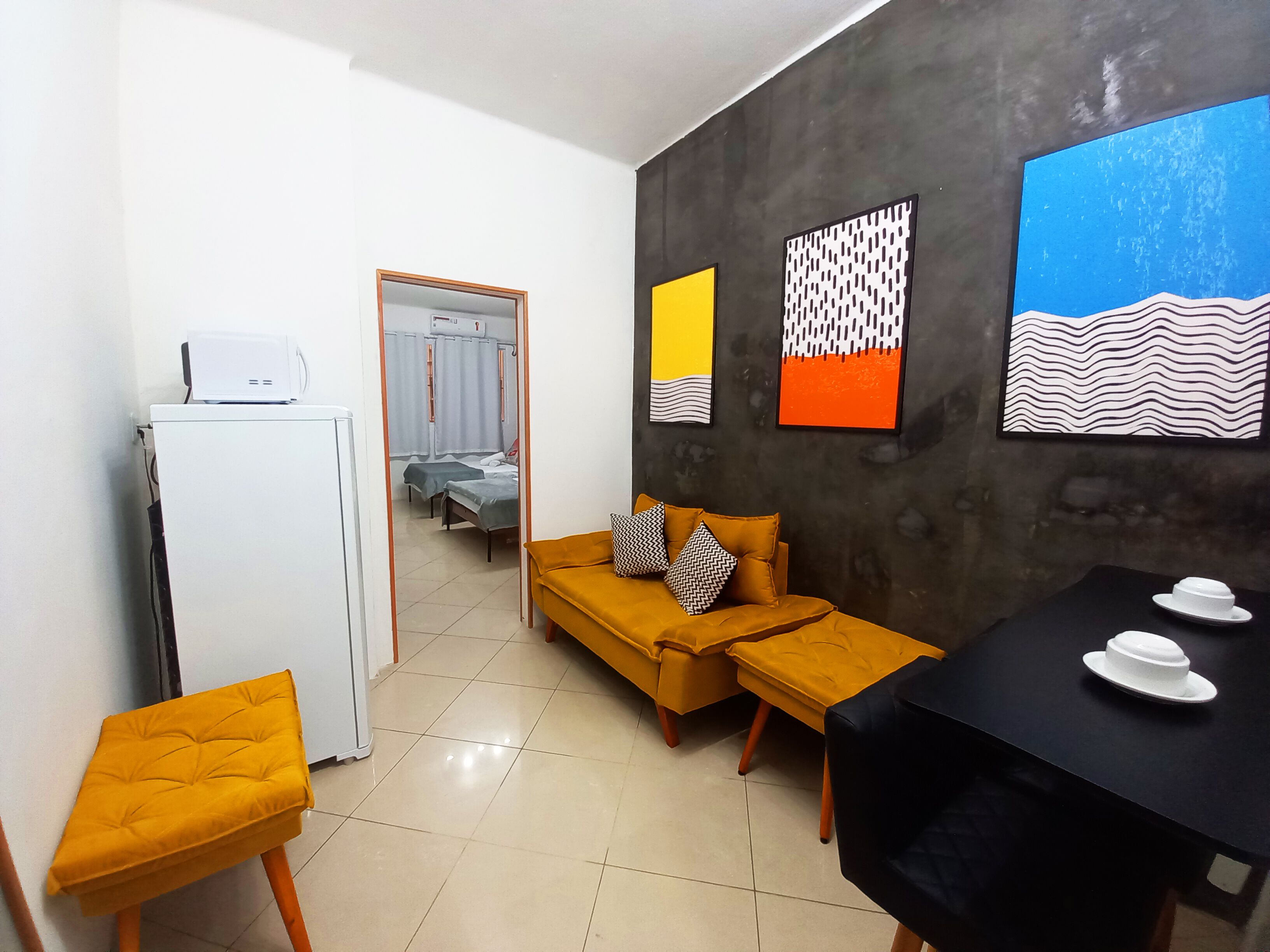 A modern hotel room with a sofa, two armchairs, a dining table, and artwork on the walls.
