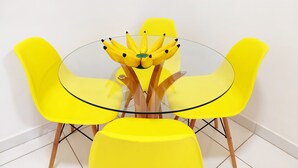 Una mesa de vidrio redonda con un centro de mesa de plátano amarillo, rodeada de sillas amarillas.