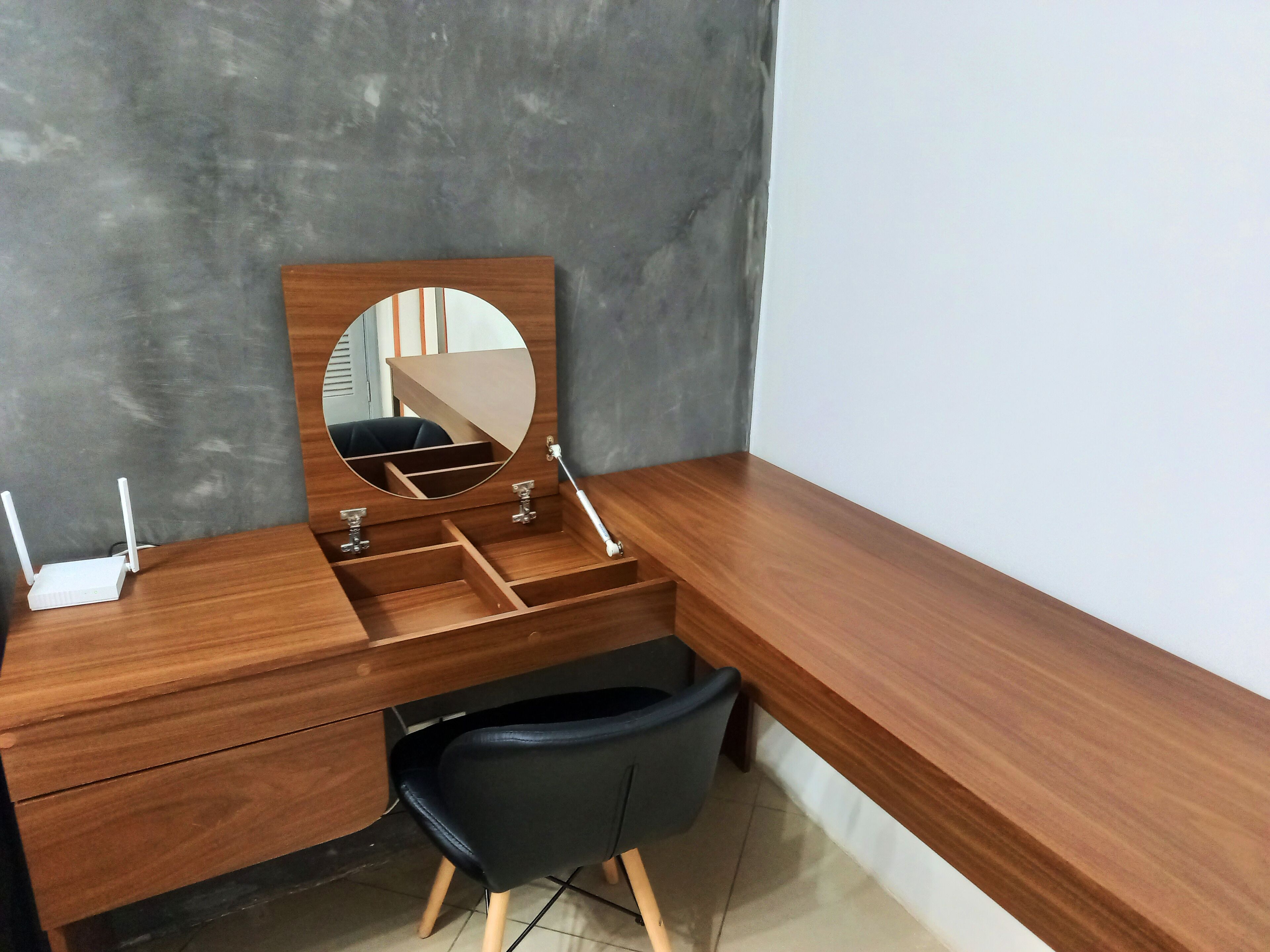 A corner desk with a mirror, a chair, and a small drawer unit.