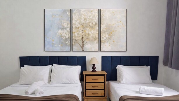 Una habitación de hotel con dos camas, una mesita de noche y tres cuadros enmarcados en la pared.