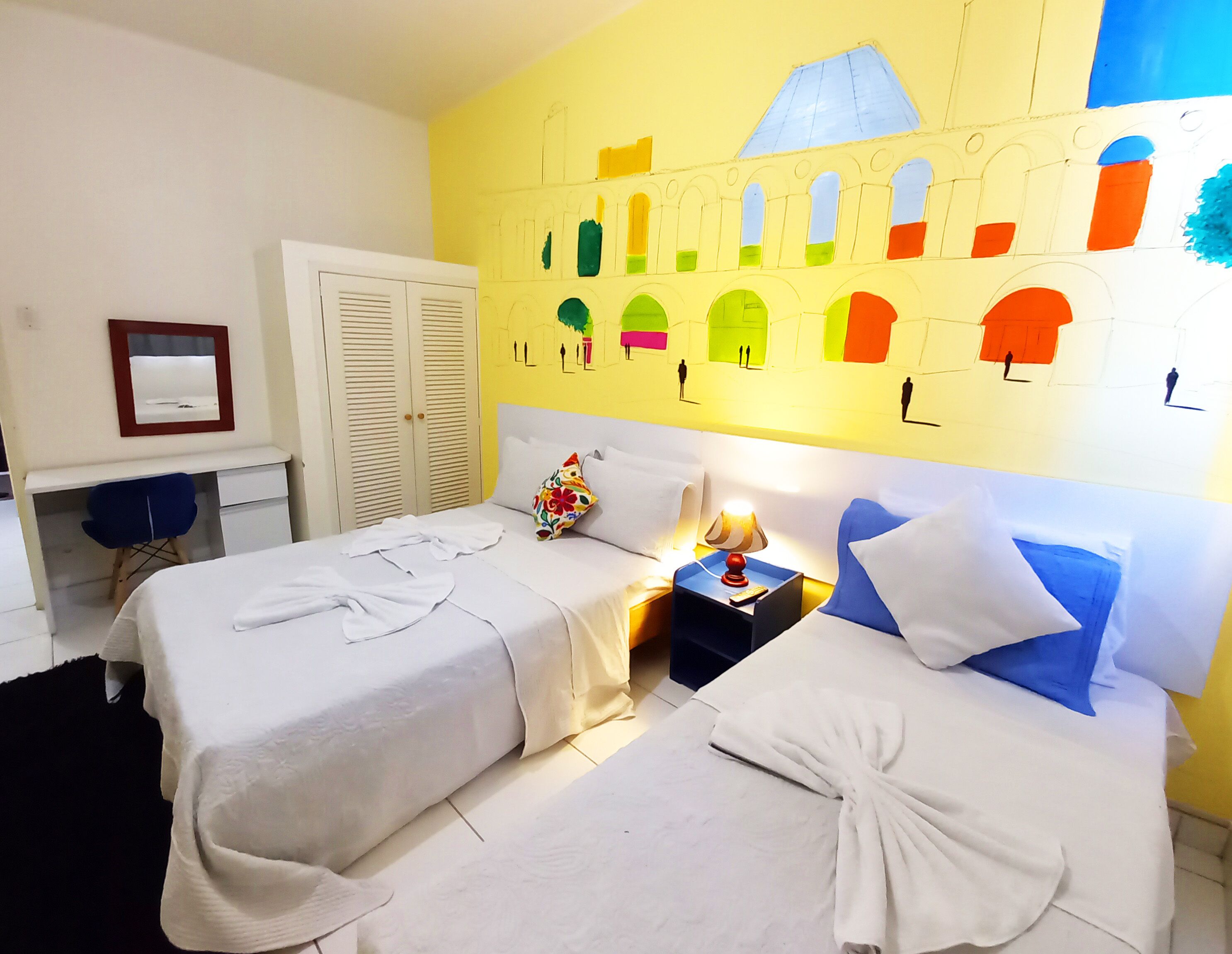 A hotel room with two beds, a desk, and a wardrobe.
