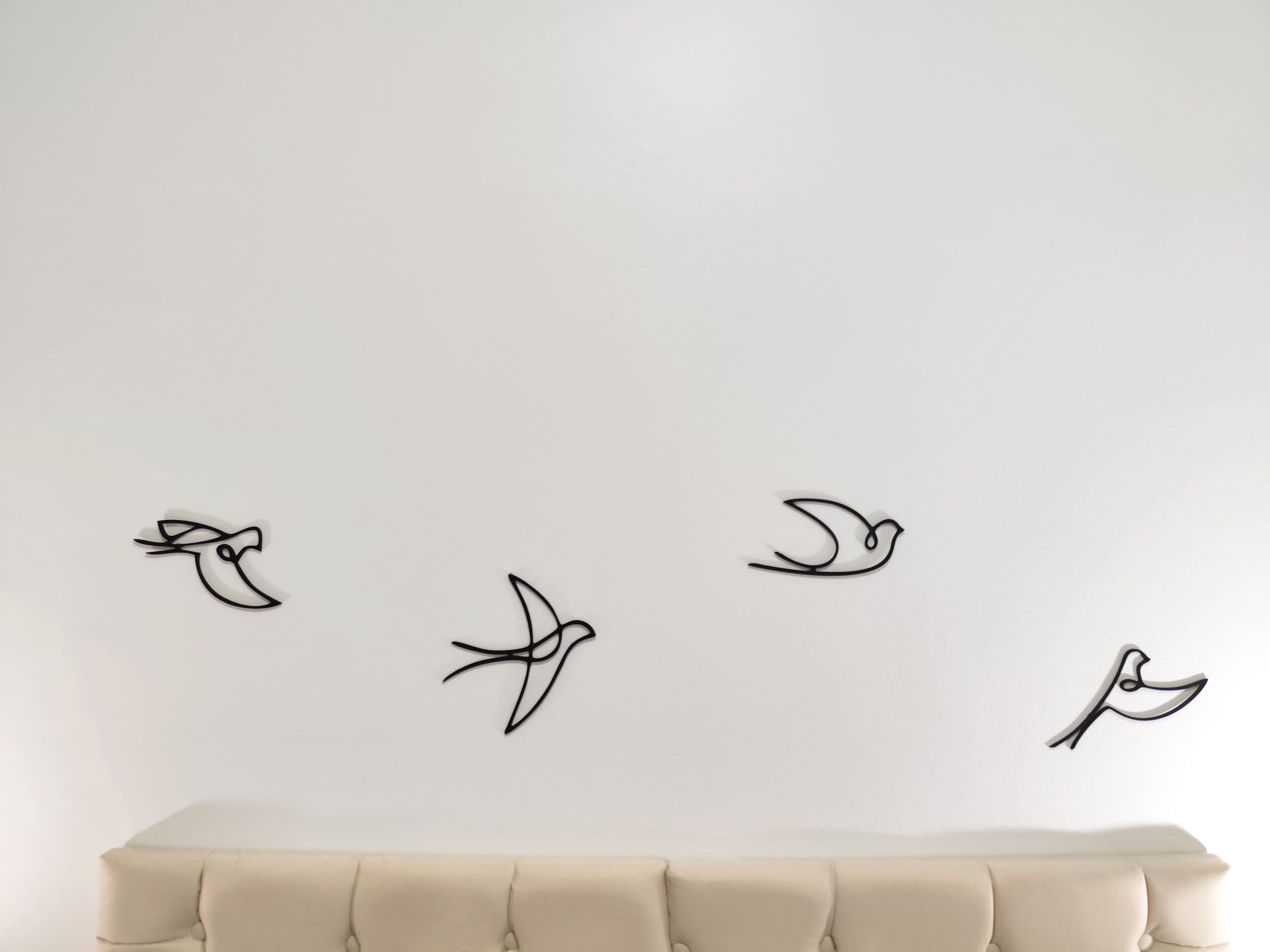 Una pared con cuatro siluetas de aves volando.