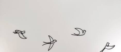 Una pared con cuatro siluetas de aves volando.