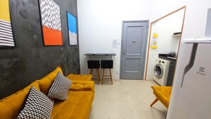 Un espacio habitable compacto con sofá, una mesa de comedor y lavadora.