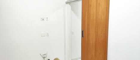 Een kamer met een schuifhouten deur, een witte airconditioning en een bureau met stoel.