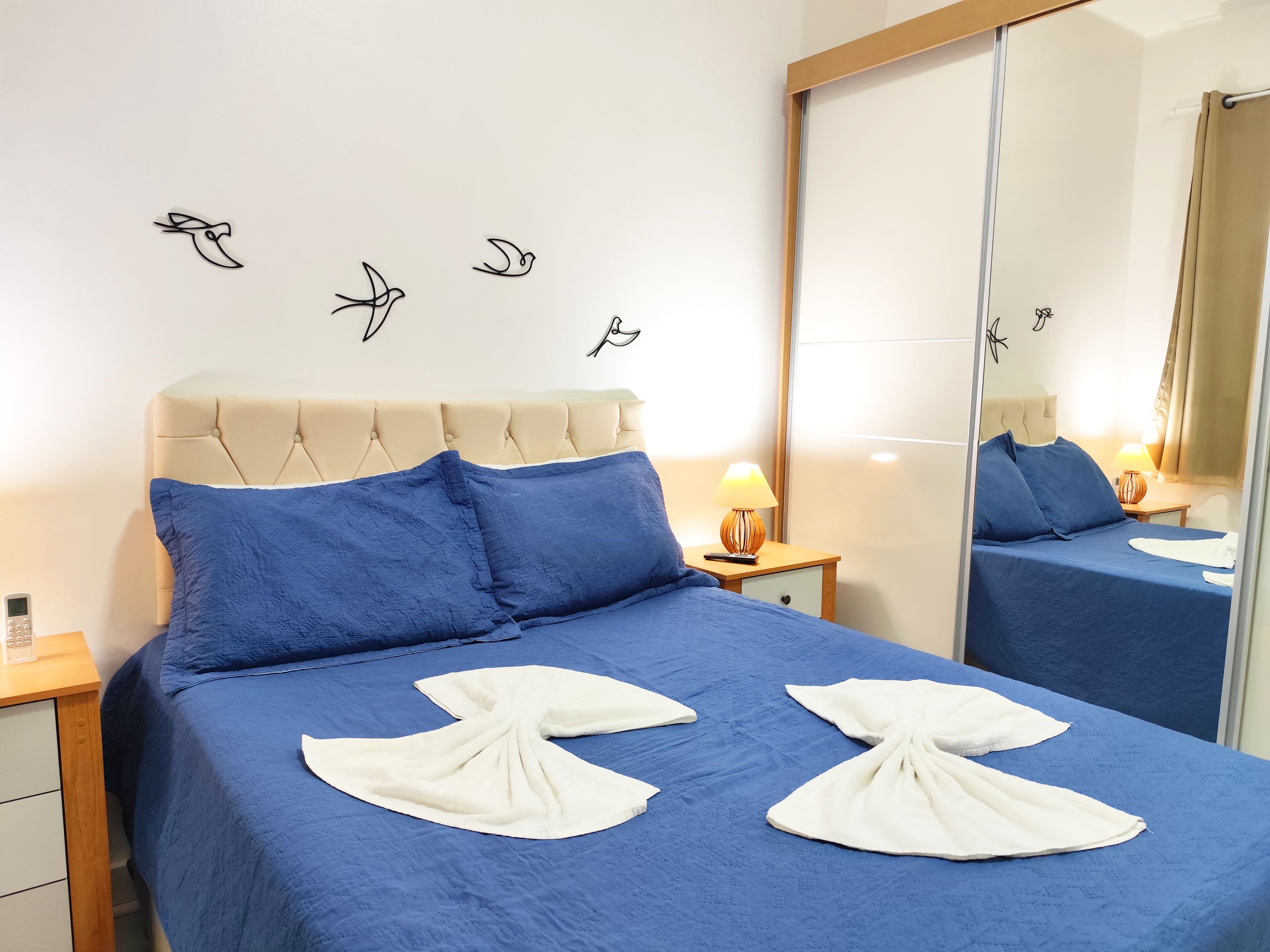 Ein Hotelzimmer mit einem Bett, einem Nachttisch, einer Lampe und einem Spiegel.