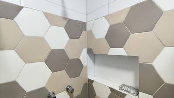 A bathroom with hexagonal patterned tiles in neutral tones, a showerhead, and a metal towel rack.