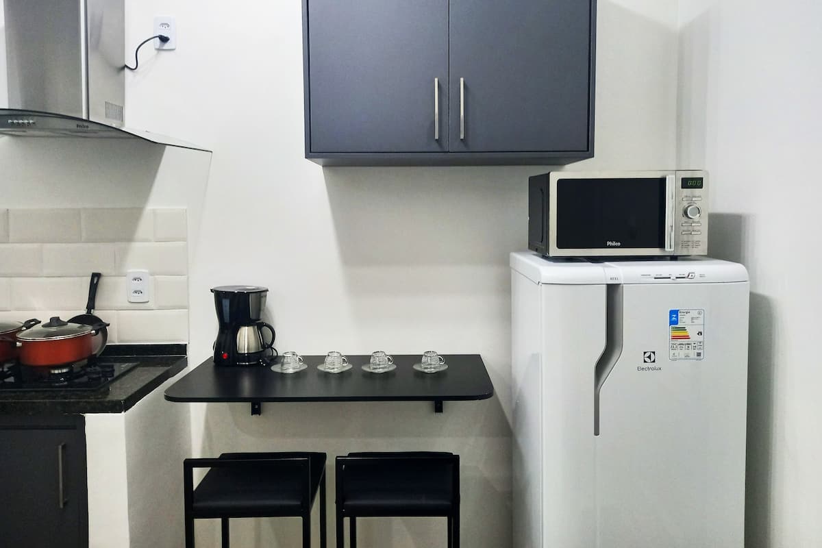 A compact kitchenette with a microwave, a coffee maker, and a small table with two chairs.