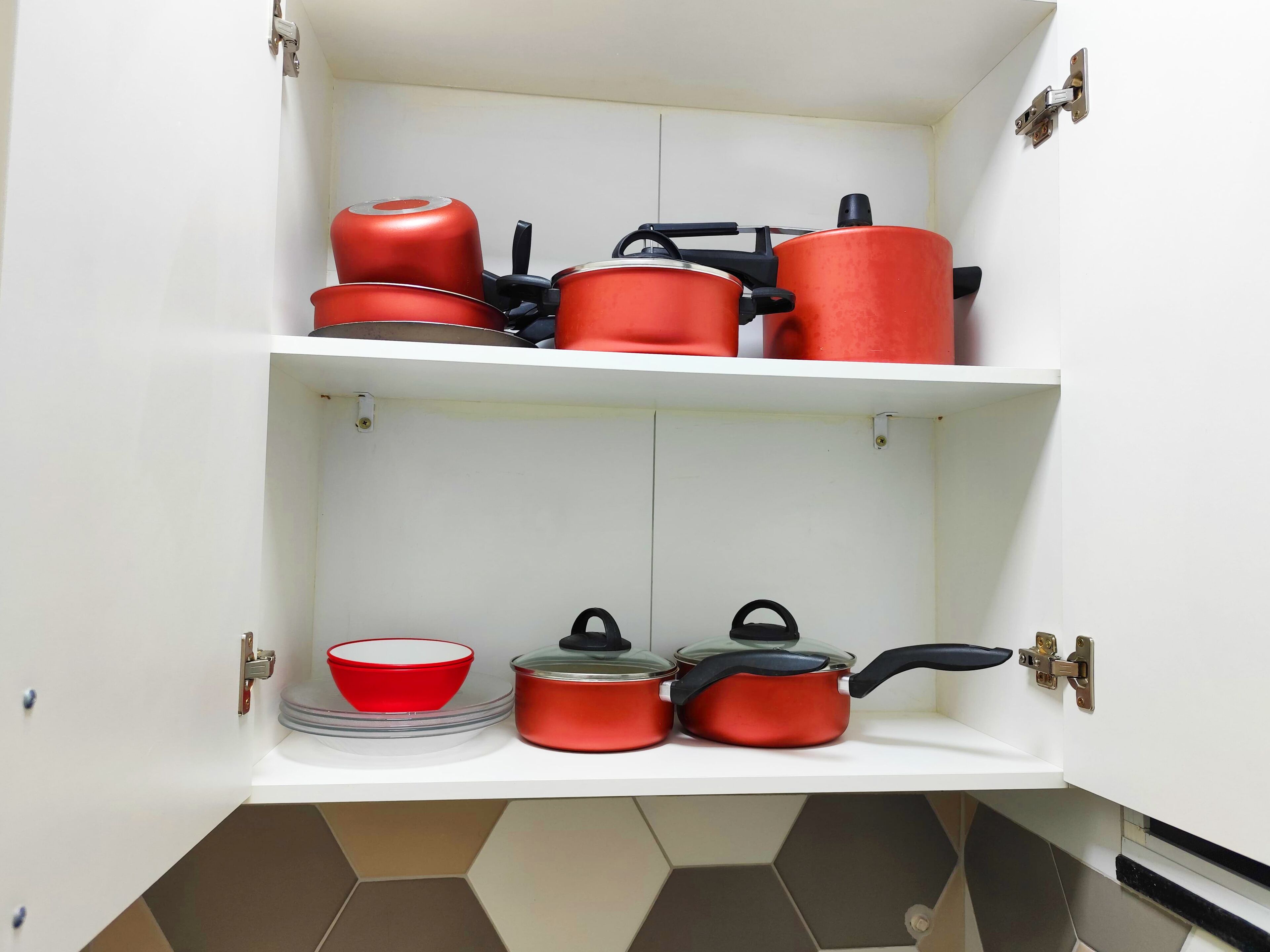 Un pensile da cucina con due ripiani, ciascuno contenente diversi utensili e pentole.