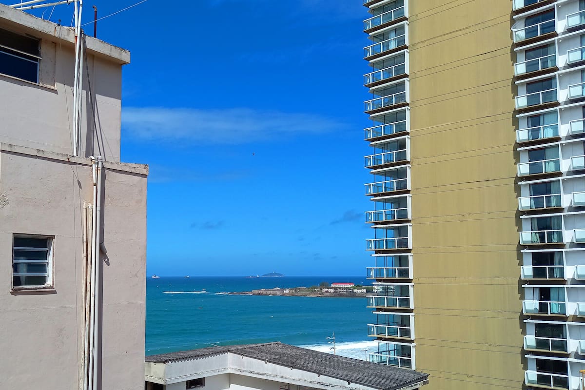 A high-rise building with multiple balconies overlooking a coastal area.