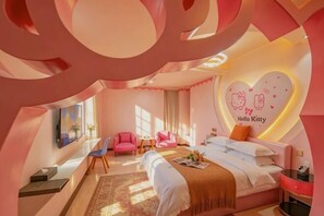 A pink-themed hotel room with a bed, two chairs, a desk, and a wall with a Hello Kitty design. - Fushan Garden Hotel (Zhangping)