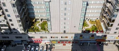 A multi-story building with a central courtyard, surrounded by parking spaces and commercial establishments.