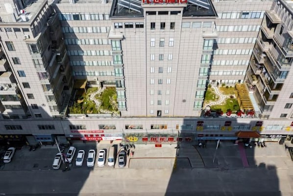 A multi-story building with a central courtyard, surrounded by parking spaces and commercial establishments.