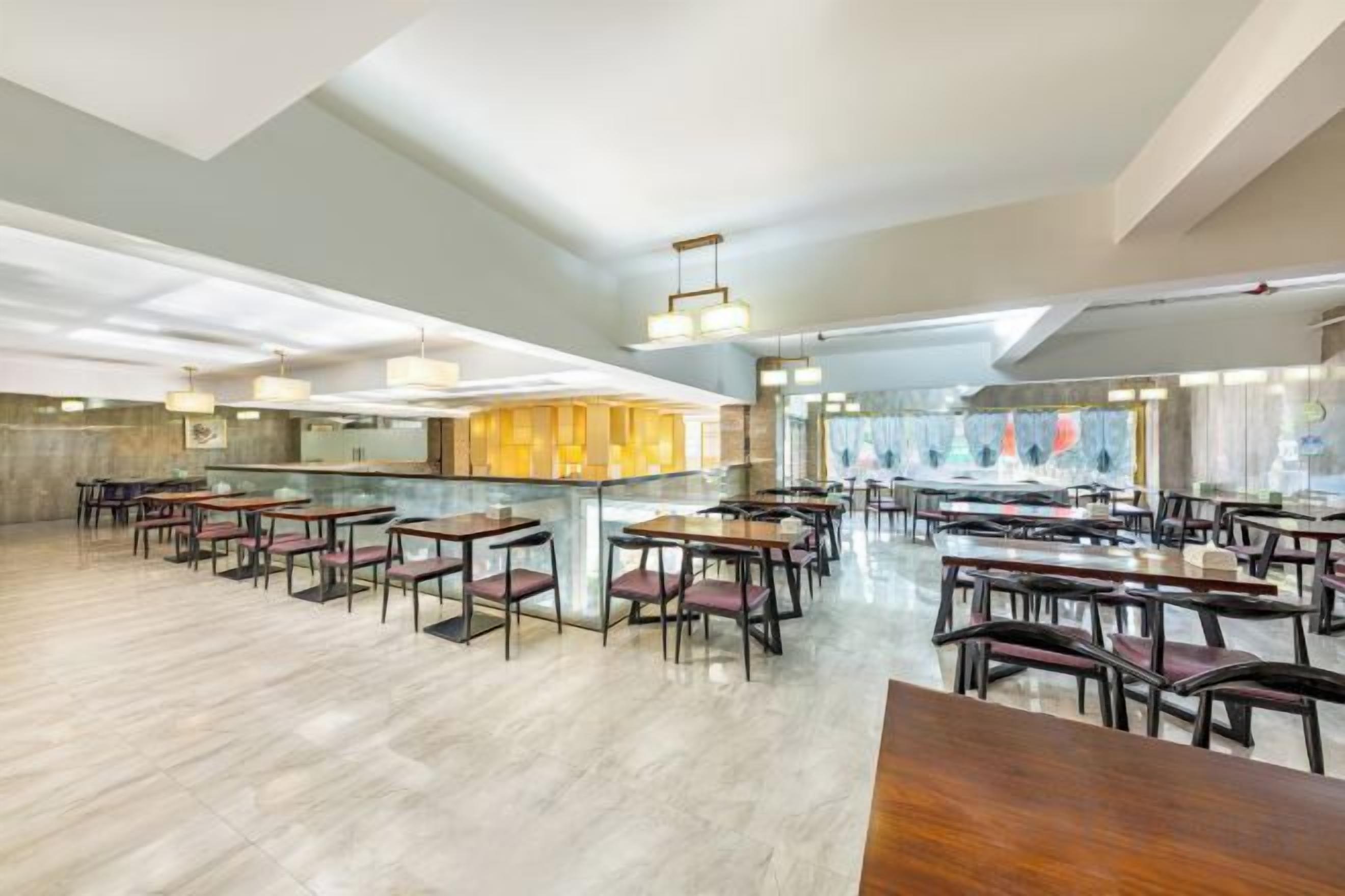 Um restaurante amplo com pé direito alto, iluminação moderna e um espaço de bar central.