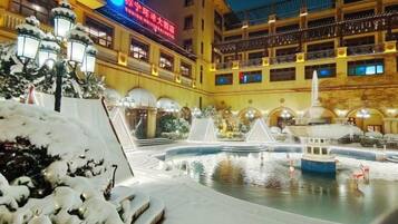 A hotel courtyard with a fountain, snow-covered plants, and a building with multiple balconies.