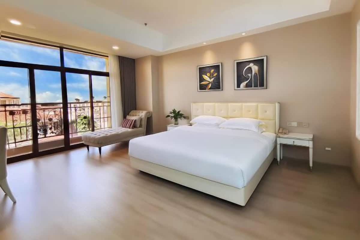 Un dormitorio con una cama grande, una mesita de noche, una silla y vistas por una ventana amplia.