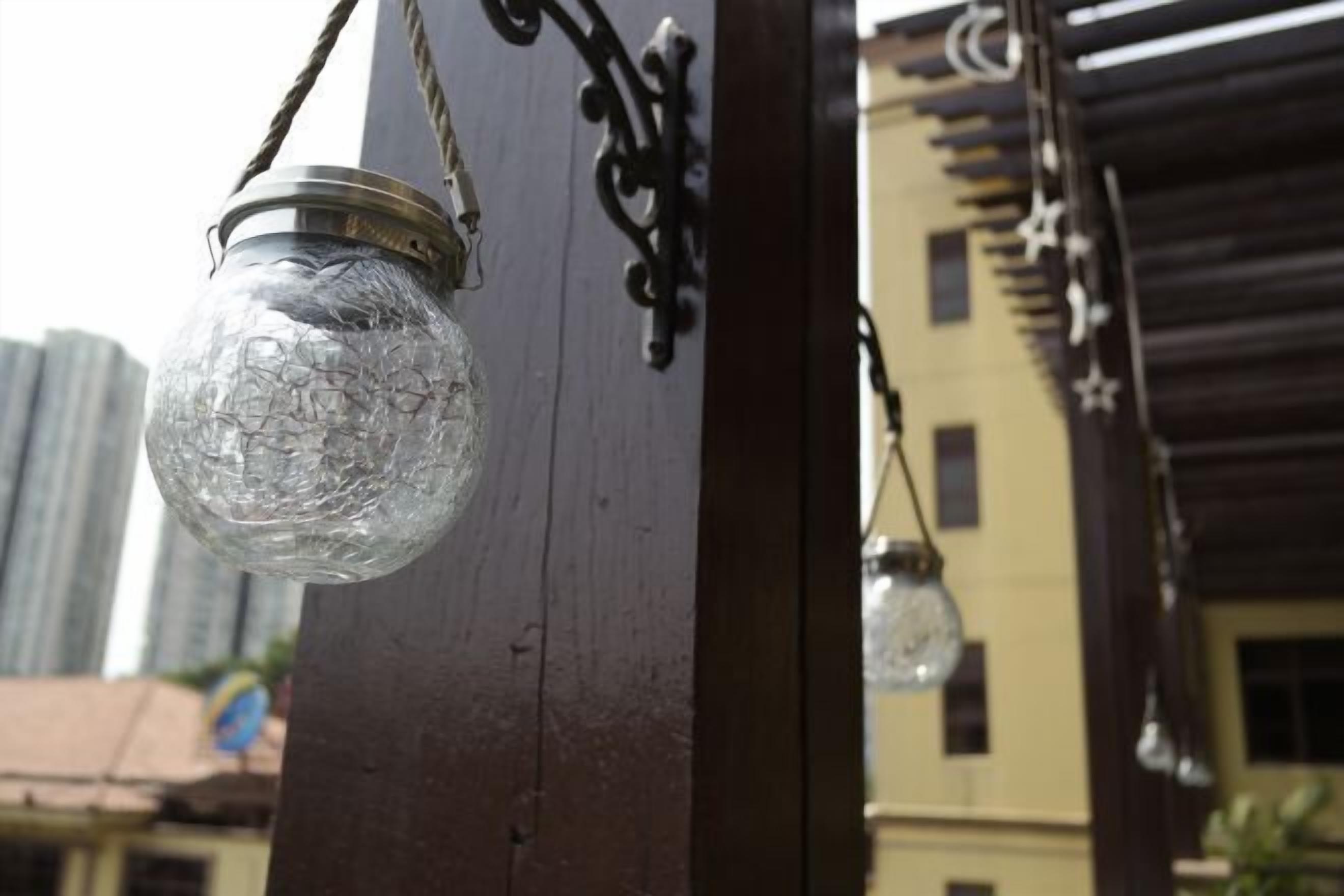 A glass bottle lantern hanging from a wooden post.