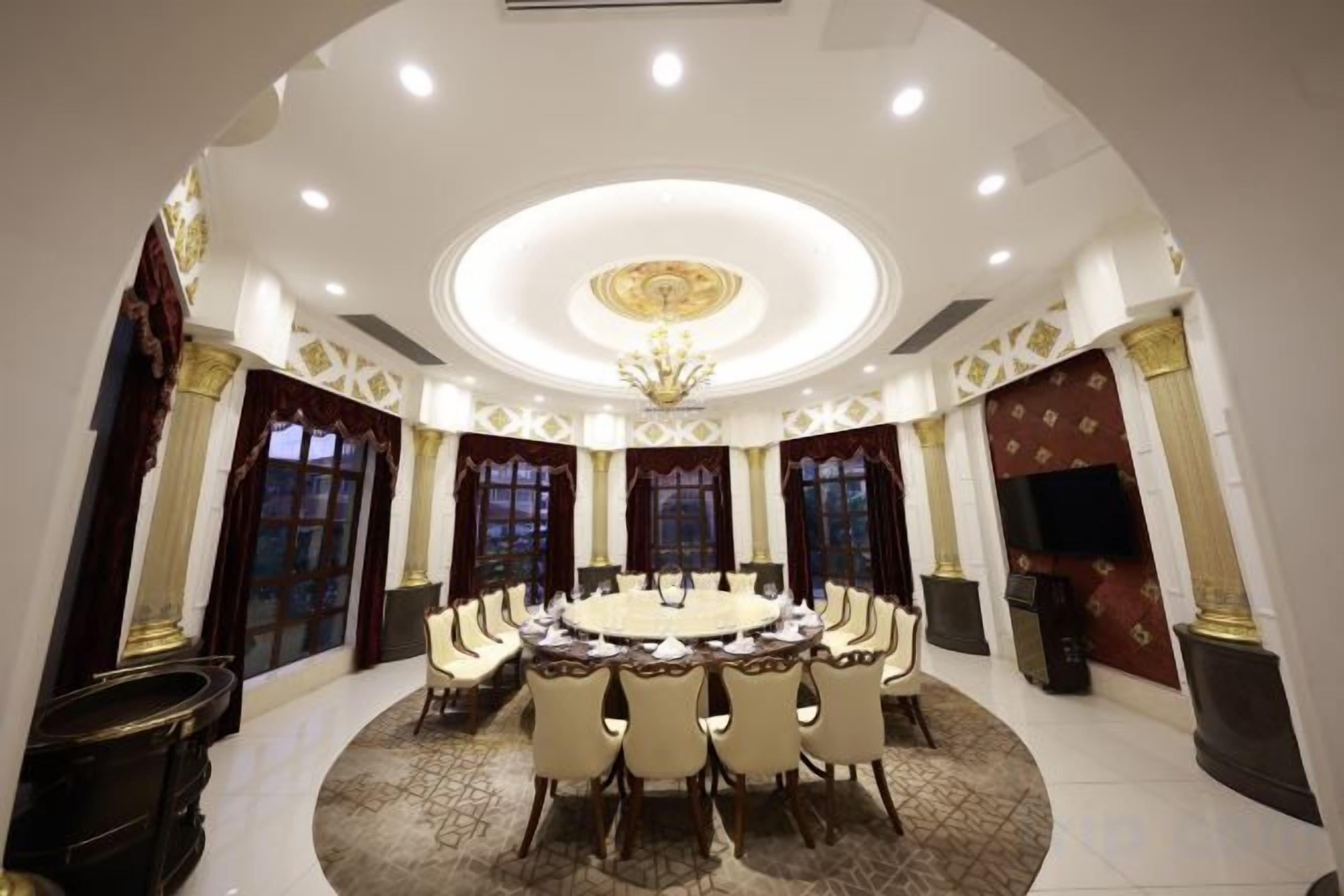 A formal dining room with a round table, chairs, and a chandelier.