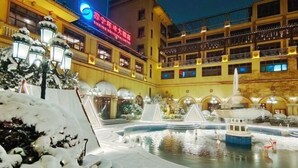 Ein Hotelinnenhof mit einem Brunnen, schneebedeckten Bäumen und einem Gebäude mit Balkonen.