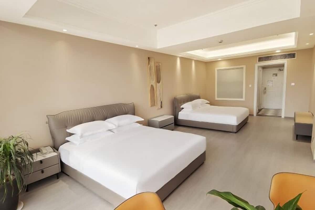 Una habitación de hotel con una cama grande, una cama más pequeña, un escritorio y una silla.
