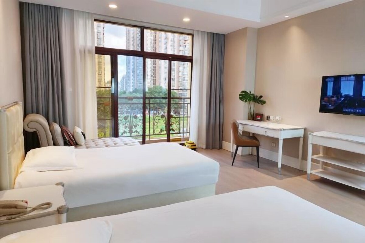 Een hotelkamer met twee bedden, een bureau, een stoel, een televisie en een balkon met uitzicht.