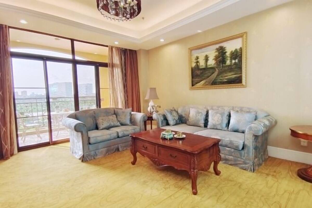 Una sala de estar con un juego de sofá, una mesa de centro, un cuadro y vistas amplias por las ventanas.