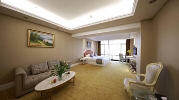 Quarto de hotel com sofá, cama, escrivaninha, cadeira e um quadro na parede.