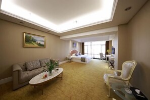 Ein Hotelzimmer mit Sofa, Bett, Schreibtisch, Stuhl und einem Bild an der Wand.