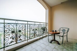 Ein Balkon mit schmiedeeisernem Geländer, zwei Stühlen und einem kleinen runden Tisch.