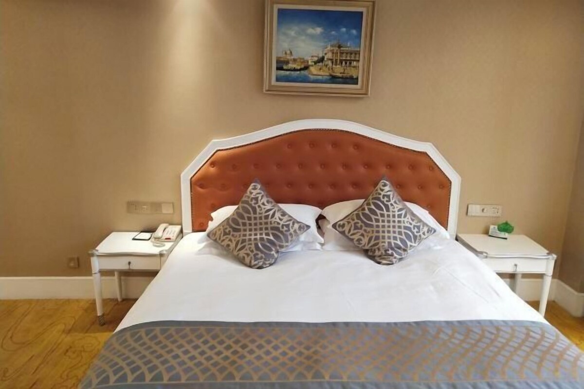 Ein Hotelzimmer mit einem großen Bett, zwei Nachttischen, einem Telefon und einem Bild an der Wand.