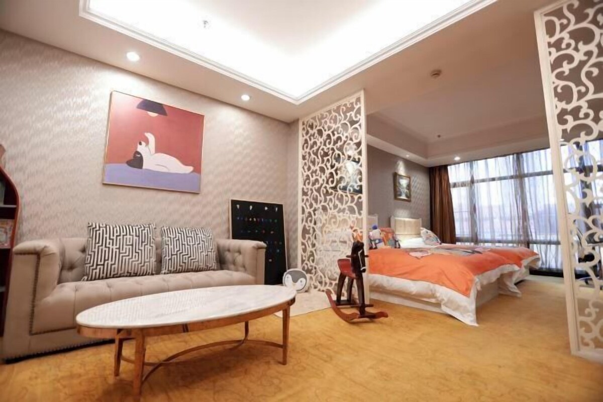 Ein geräumiges Zimmer mit einer Couch, einem Bett, einem Tisch und einer dekorativen Wandverkleidung.