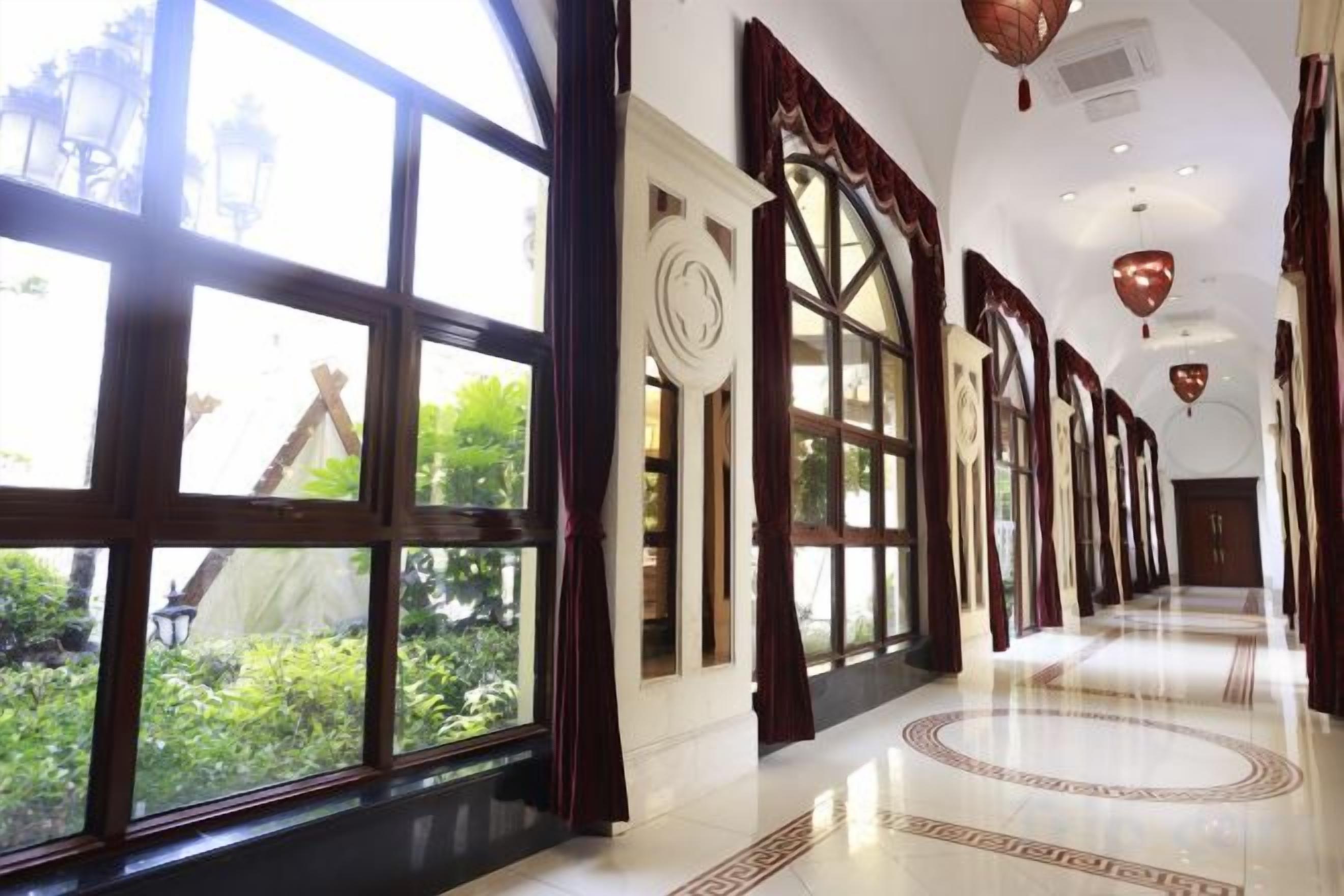 A hallway with large windows, a patterned floor, and a curved ceiling.
