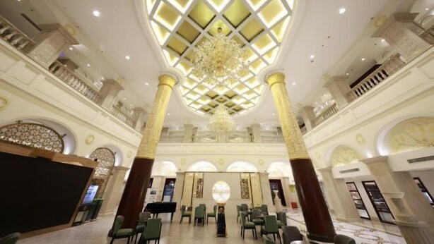 Eine geräumige Lobby mit hoher Decke, aufwendigen Kronleuchtern und klassizistischer Architektur.