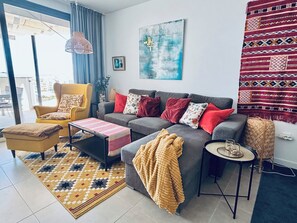 A modern living room with a sofa, armchair, coffee table, and a patterned rug.