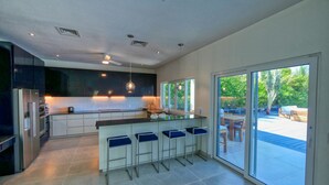 A modern kitchen with a central island, built-in appliances, and a large sliding glass door leading to an outdoor area.