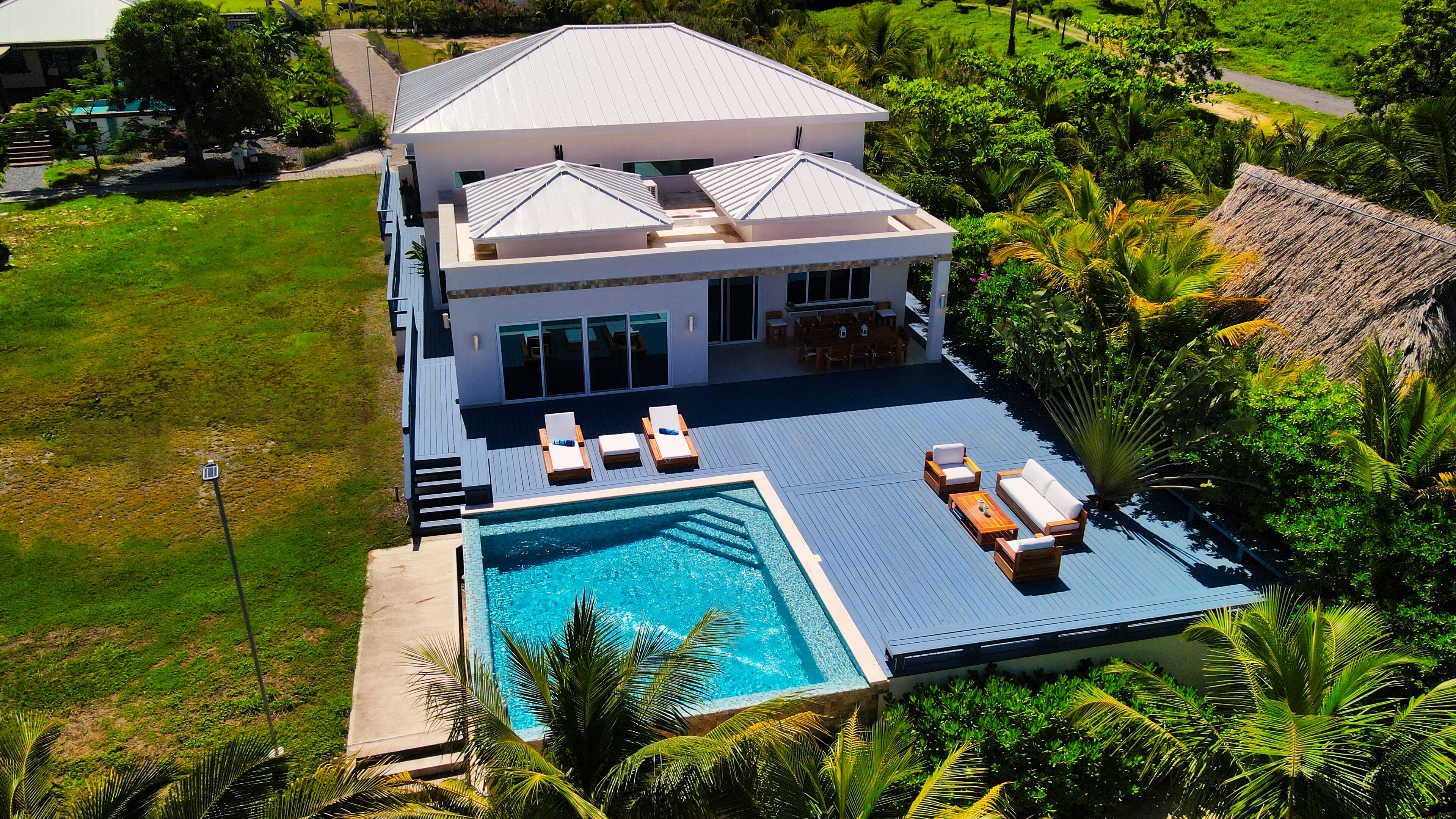 A modern house with a swimming pool, a covered patio, and lush greenery.