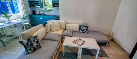 Een moderne woonkamer met een modulaire bank, een klein wit tafeltje en een keuken op de achtergrond.