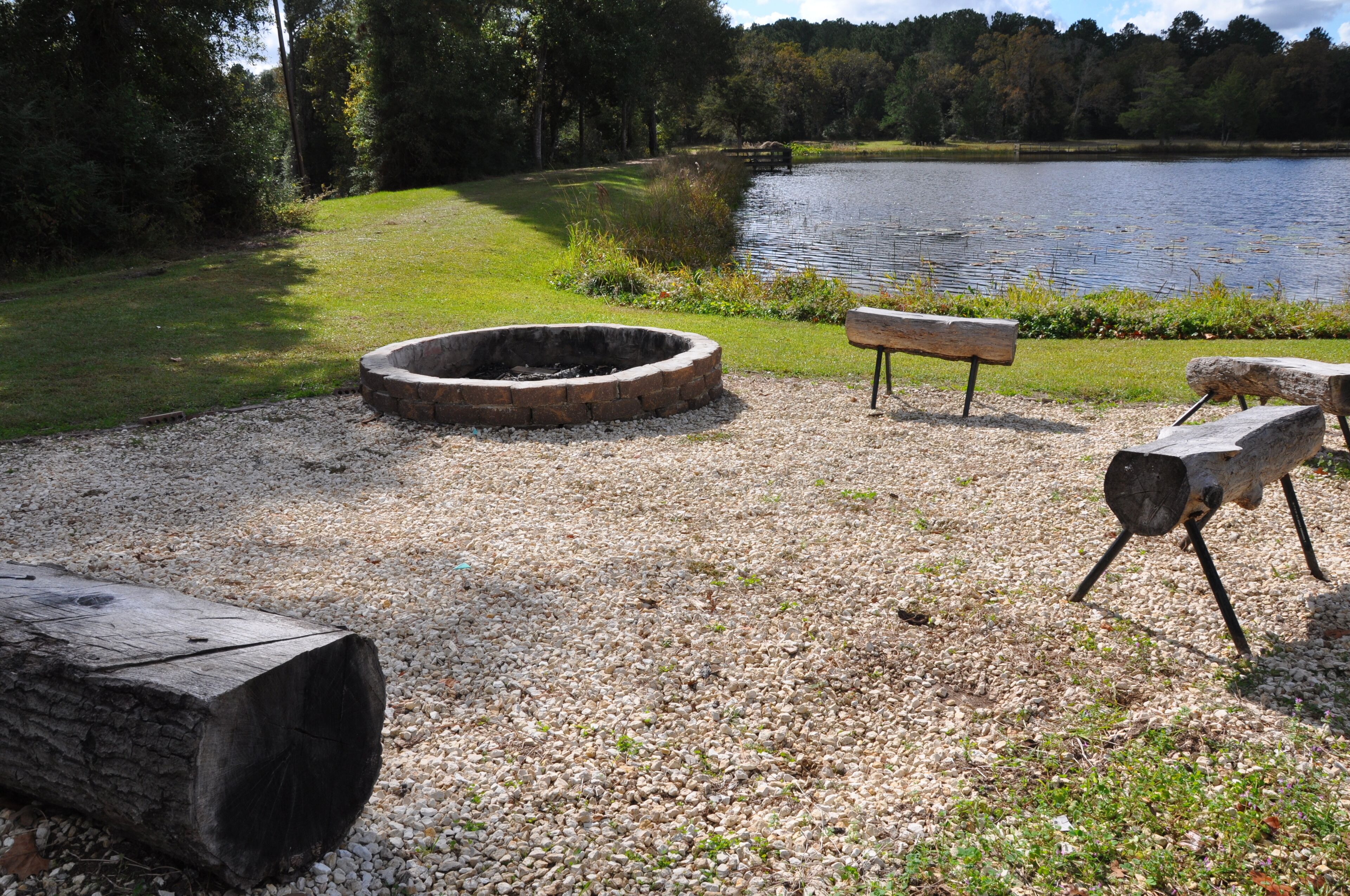 A gravel area with a fire pit, a bench, and a log.