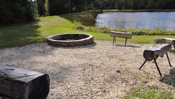 A gravel area with a fire pit, a bench, and a log.