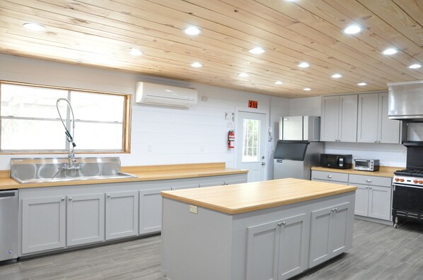 Una cocina moderna con armarios grises, encimera de madera, lavaplatos empotrado, microondas, estufa y señal de salida.