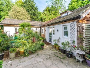 A garden with potted plants and a stone pathway leading to a white building with a tiled roof. - The Little House in Hull (Hull, near Beverley)