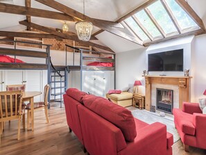 Un salon chaleureux avec un canapé rouge, un plancher en bois, une cheminée et un téléviseur fixé au mur.