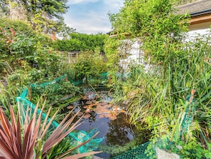 A serene garden with a pond, lush greenery, and a traditional building in the background. - The Little House in Hull (Hull, near Beverley)