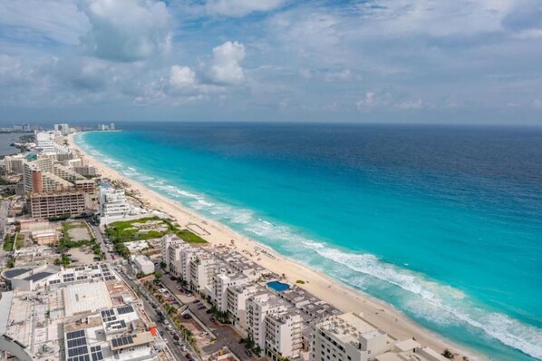 A coastal cityscape with a beachfront hotel, including buildings, a beach, and the ocean.